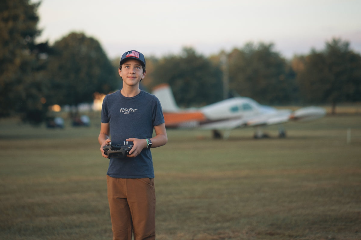 a young man standing in a field holding a camera