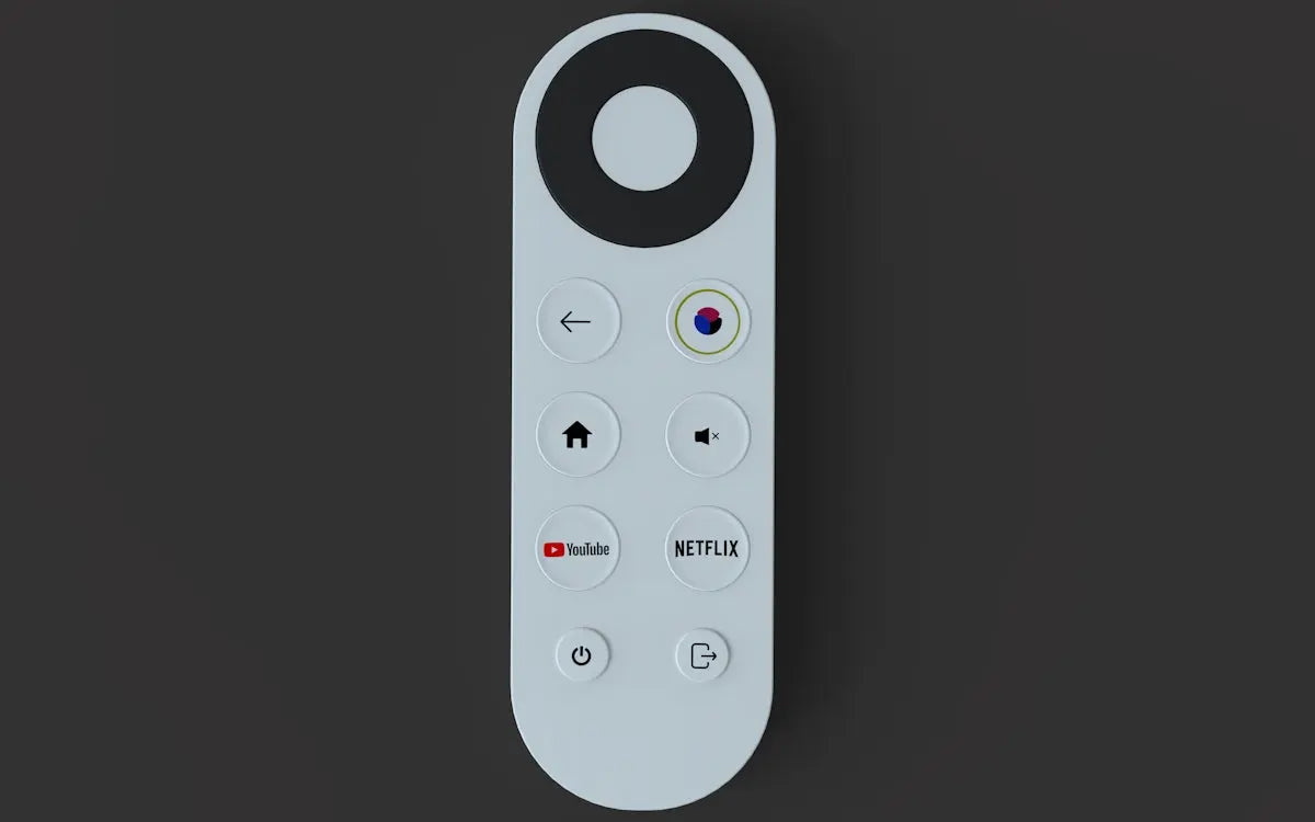 A white remote lying on a dark surface.