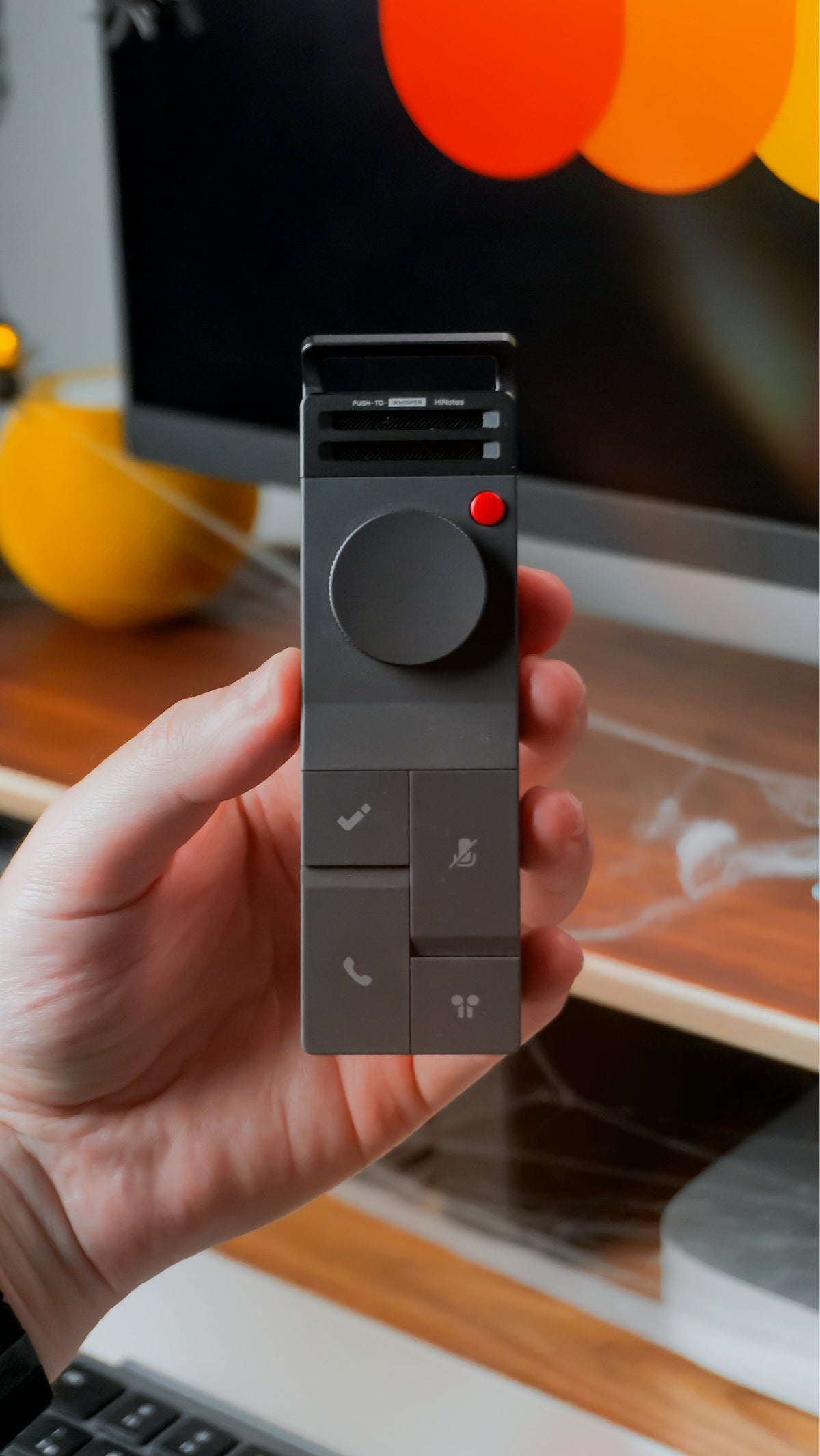 Hand holding a digital controller with buttons and dial