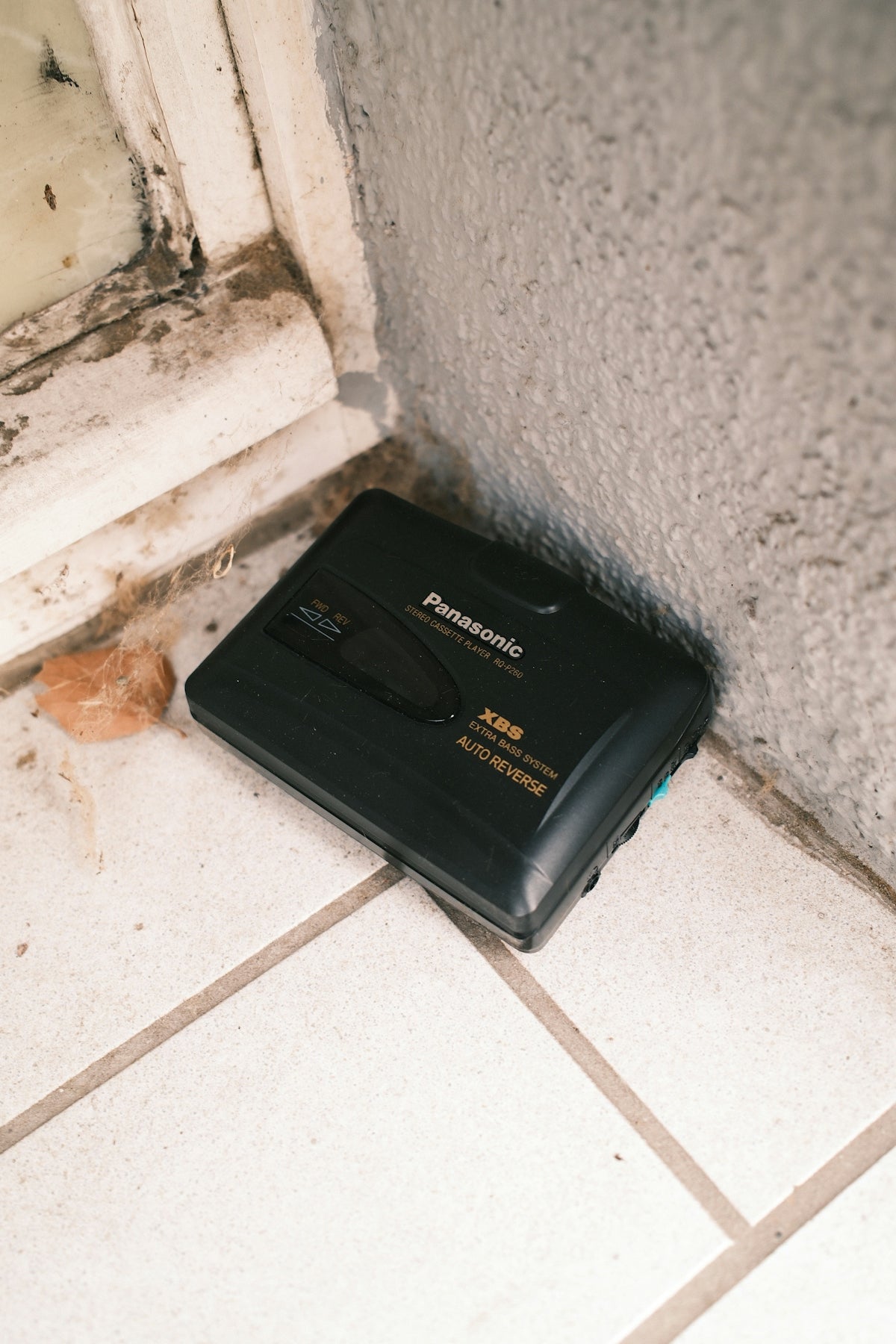 A black panasonic portable cassette player sits on tiled floor.